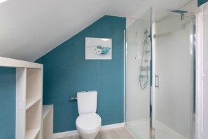 Ein Badezimmer mit Toilette, Duschkabine aus Glas und einer Wand in Türkis.