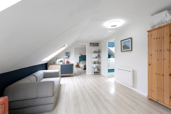 A spacious room with a high ceiling, a built-in sofa, a wooden wardrobe, and a radiator.