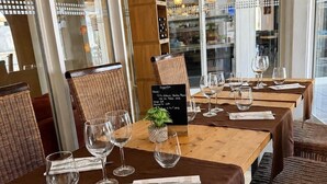 A restaurant with wooden tables and wicker chairs, a menu stand, and hanging pendant lights. - La parenthèse Camarguaise (Gallargues-le-Montueux)