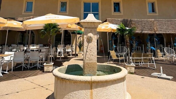 A courtyard with outdoor seating, a fountain, and string lights. - La parenthèse Camarguaise (Gallargues-le-Montueux)