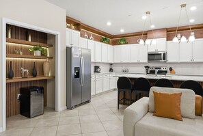 Eine moderne Küche mit weißen Schränken, einem integrierten Kühlschrank, einer Mikrowelle und einem Essbereich mit einer Couch und Stühlen.