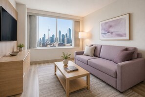 Ein modernes Hotelzimmer mit Blick auf die Stadt, inklusive Sofa, Couchtisch, Fernseher und Lampe.