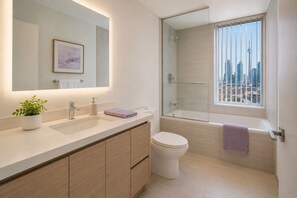 Ein modernes Badezimmer mit einem großen Spiegel, einem Waschbecken, einer Toilette und einer Badewanne.