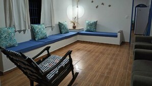 A living room with a built-in bench, a rocking chair, and a wall-mounted light fixture. - Grandma's house in Piúma: Backyard, Porch and 3 Bedrooms (Piúma)