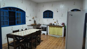 A compact kitchen with a dining table, chairs, a stove, and a refrigerator. - Grandma's house in Piúma: Backyard, Porch and 3 Bedrooms (Piúma)