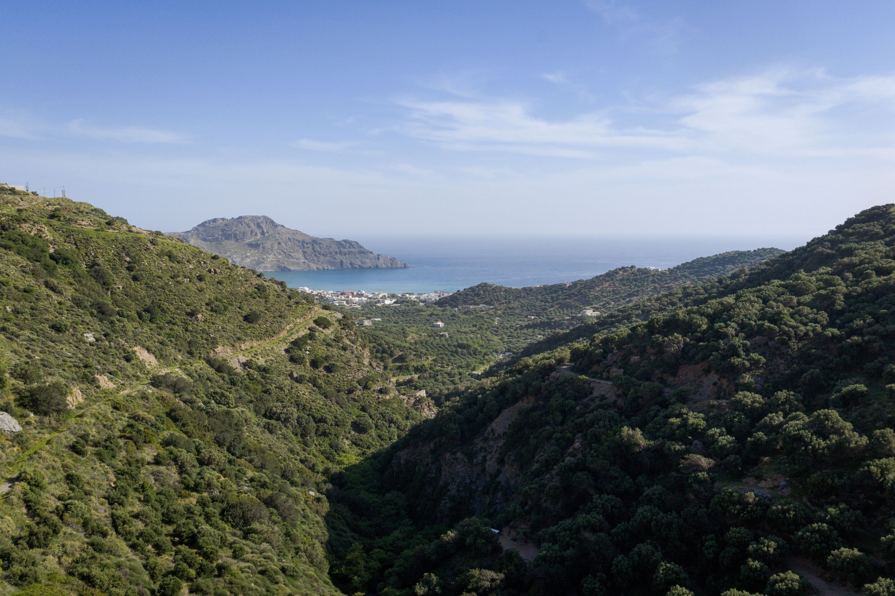 Un paysage montagneux avec une vallée et une vue lointaine sur la mer.