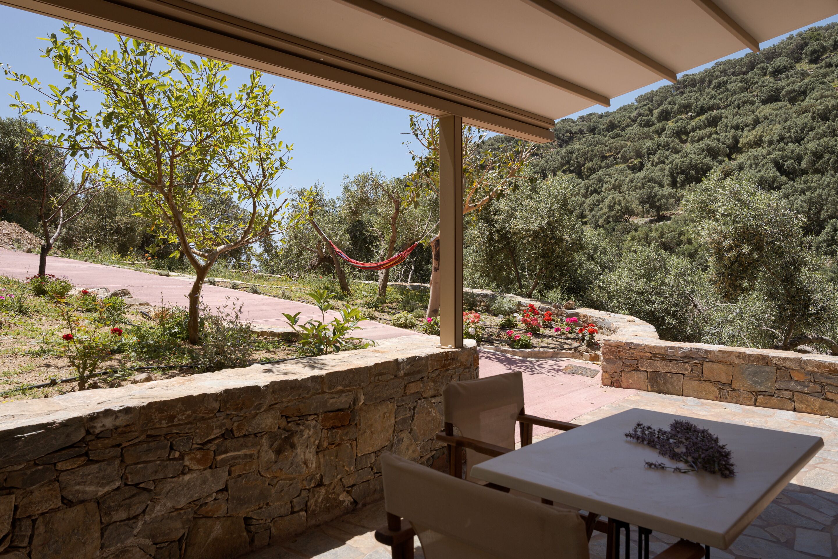 A covered patio with stone walls, a hammock, and a table with a bouquet.