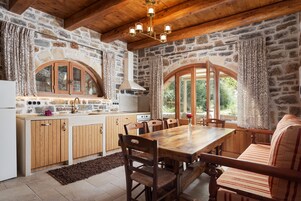 Une cuisine rustique avec des murs en pierre, des meubles en bois et de grandes fenêtres.