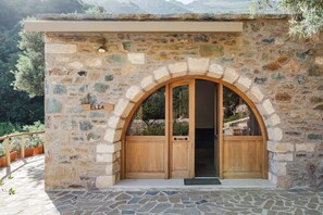 Un edificio de piedra con una entrada de madera, una placa con el nombre 'ELIA' y un área pavimentada con piedra.