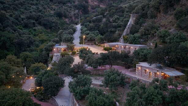 A hillside property with multiple buildings, a central pathway, and surrounding greenery. - Manelis Mills Estate - Guest Houses (Myrthianos Plakias)