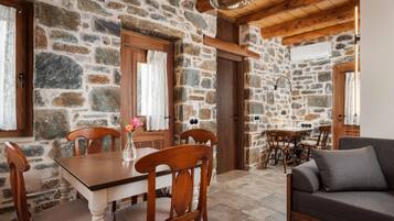 A stone-walled room with a wooden dining table, chairs, and a sofa.