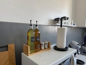 Uma bancada de cozinha com dois frascos de óleo, um suporte para toalhas de papel e um micro-ondas.