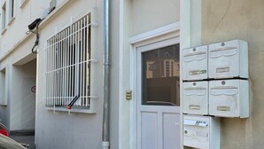 Un edificio blanco con una puerta, buzones y un contenedor de basura.