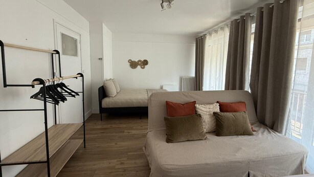 Una habitación con cama, zona de estar, perchero y radiador.