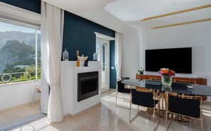 Un salon moderne doté d’une cheminée, d’un coin repas et d’un grand téléviseur.
