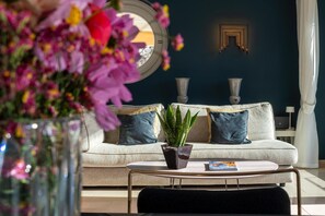 Un salon avec un canapé, deux vases, une plante en pot et un magazine sur une table basse.