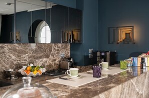 A modern kitchen with a marble backsplash, stainless steel appliances, and a fruit bowl.