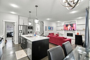 A modern kitchen with a central island, stainless steel appliances, and pendant lighting. - Spacious Modern Calgary Home | 3 Bedrooms + 2 Bonus Rooms (Calgary)