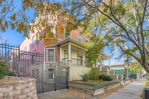 Ein zweigeschossiges Wohngebäude mit einer Veranda, einem verschlossenen Eingangsbereich und einem kleinen Vorgarten.