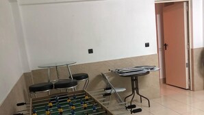 Una stanza con un tavolo da calcio, un tavolino con sedie e una porta.