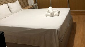 Una camera d'albergo con un letto, una testiera in legno, un armadio capiente e un termosifone.
