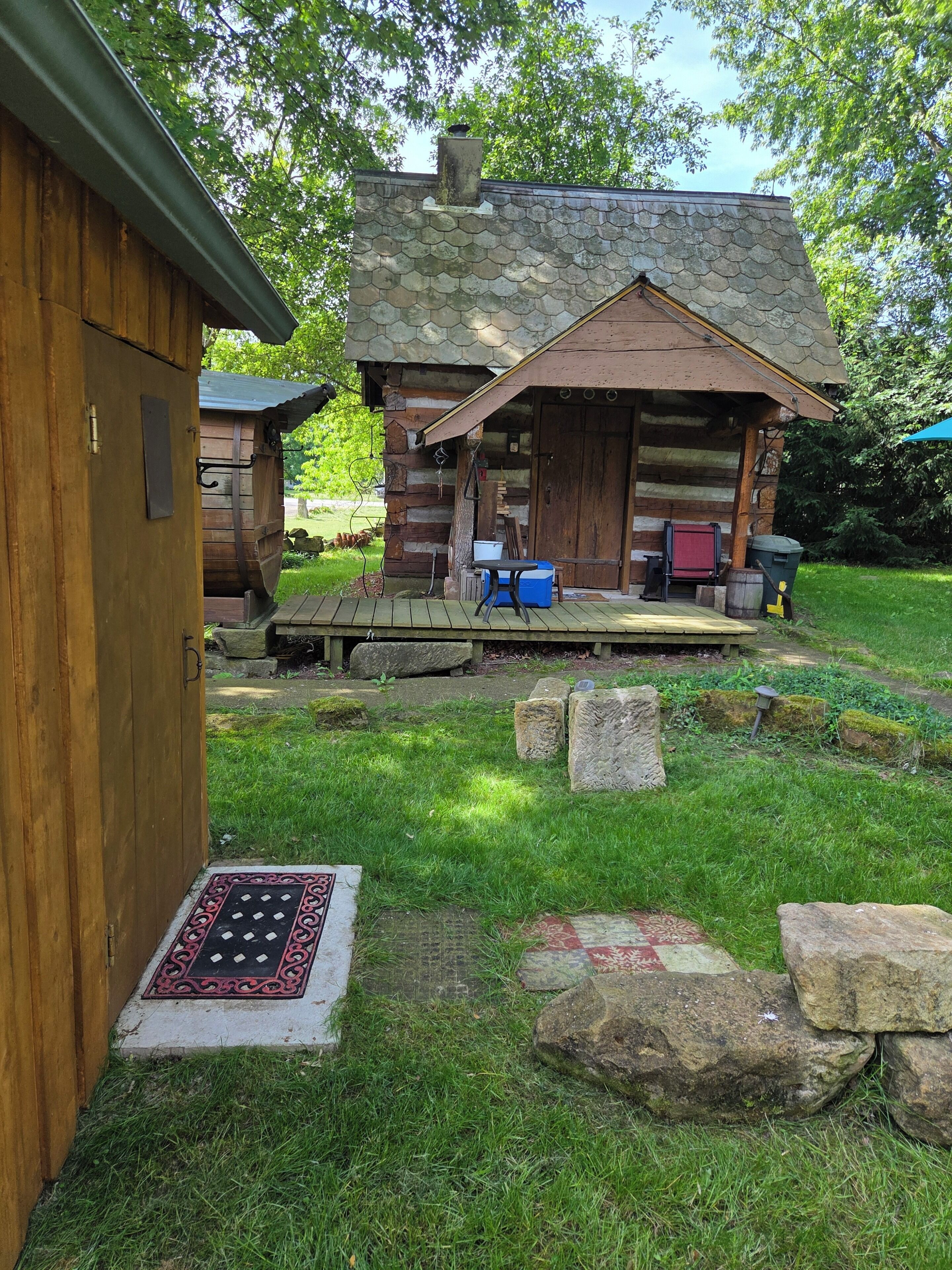 A rustic cabin with a stone exterior, a wooden porch, and a small outdoor seating area.. Charming 1-bedroom cabin in Medina perfect for a cozy getaway