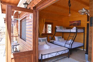 Une cabane en bois avec des lits superposés, une petite table, une lampe et un tableau accroché au mur.