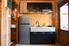A compact kitchen with a refrigerator, sink, and wooden cabinets.