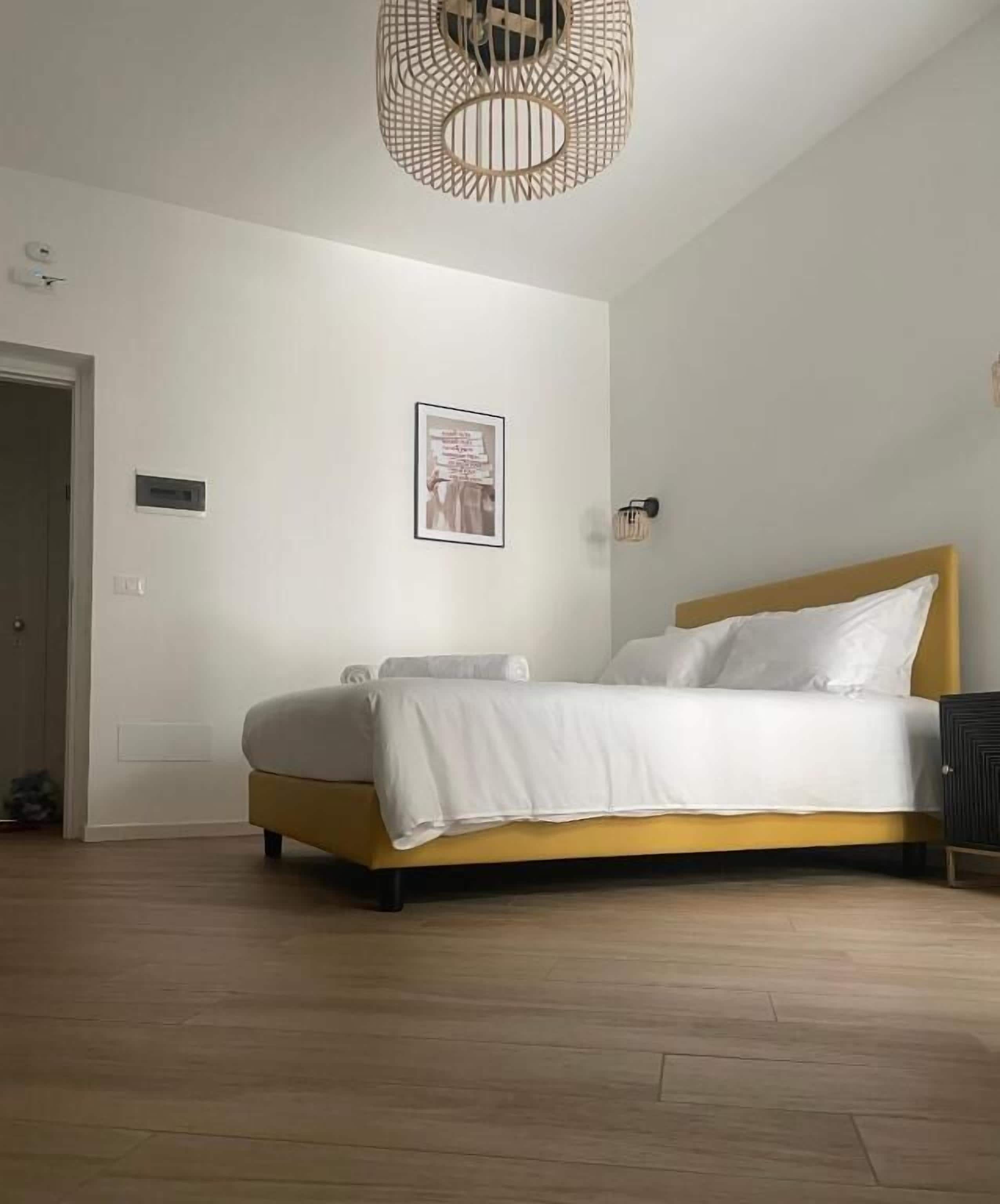 A bedroom with a bed, a wall-mounted light fixture, and a framed picture.