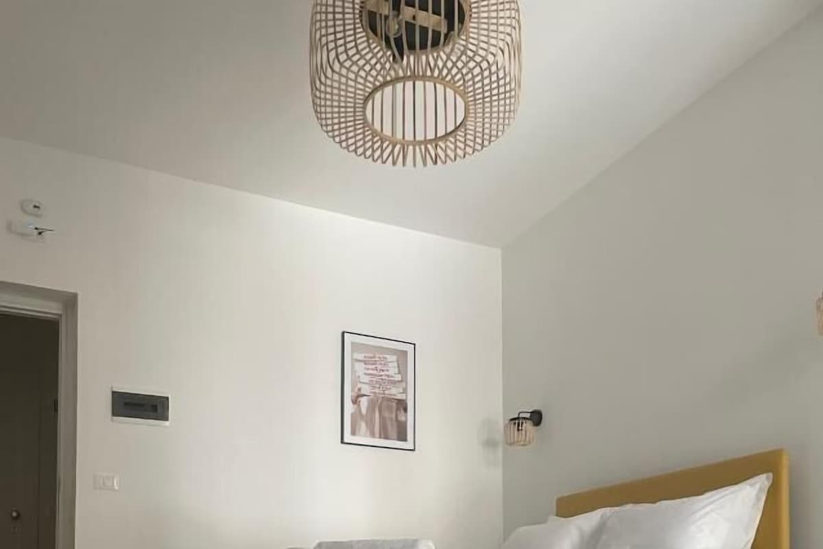 A bedroom with a bed, a wall-mounted light fixture, and a framed picture.