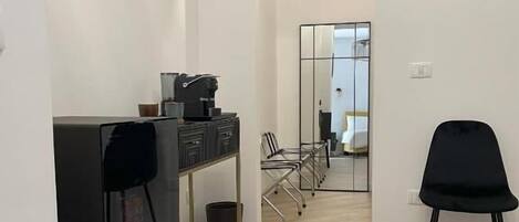 A modern interior with a long hallway, a desk with a chair, and a large mirror reflecting the room.