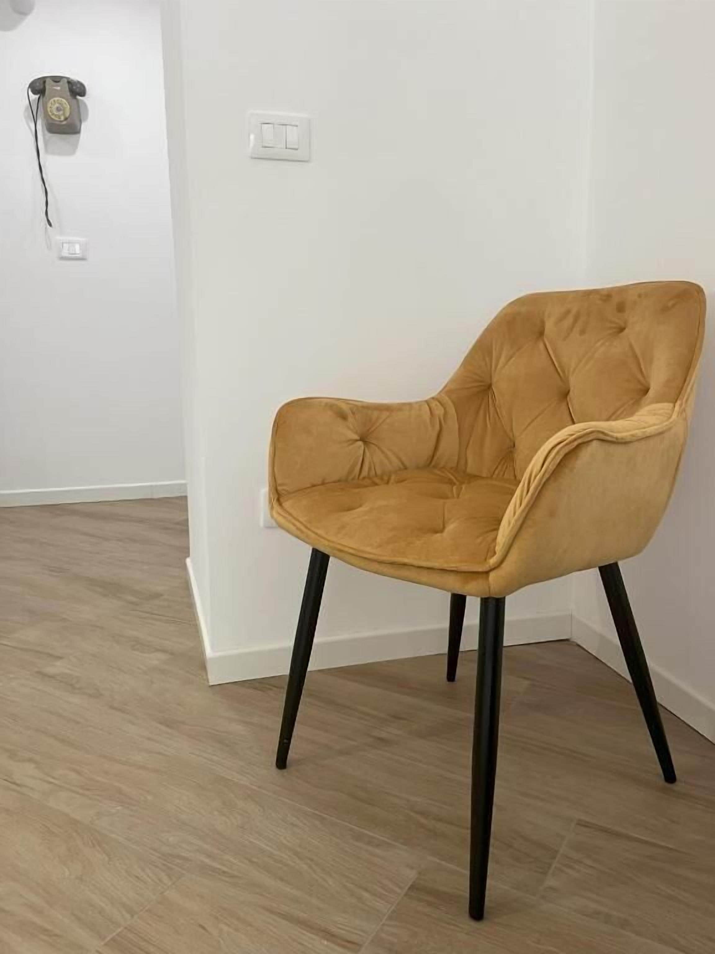 A single chair with a cushioned seat and back, black legs, and a light-colored fabric.