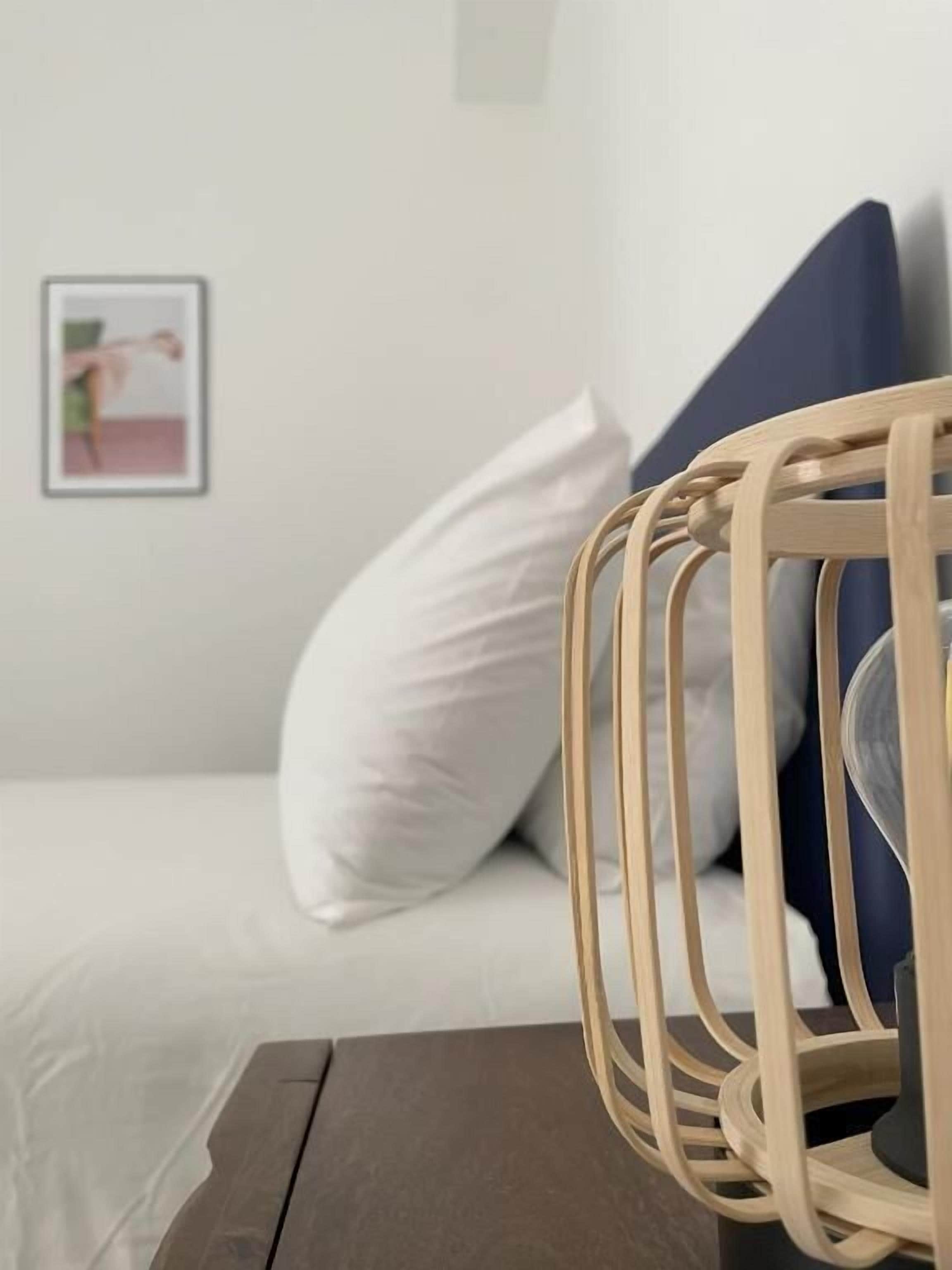 A bed with white bedding, a wooden headboard, and a blue pillow.