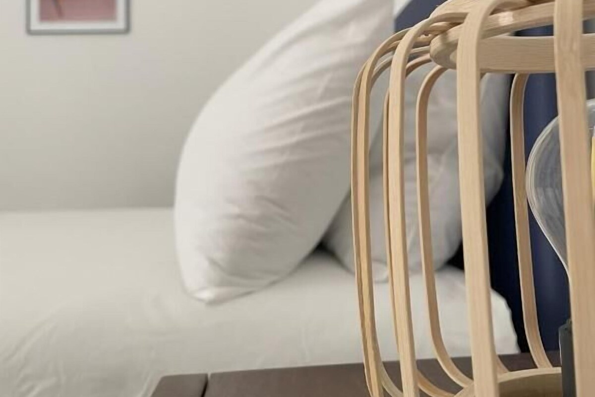 A bed with white bedding, a wooden headboard, and a blue pillow.