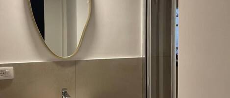 A bathroom with a white sink, a mirror with a gold frame, and a glass shower enclosure.