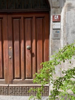 A wooden door with a metal intercom and a sign above it. - Ca' Semu (Catania)
