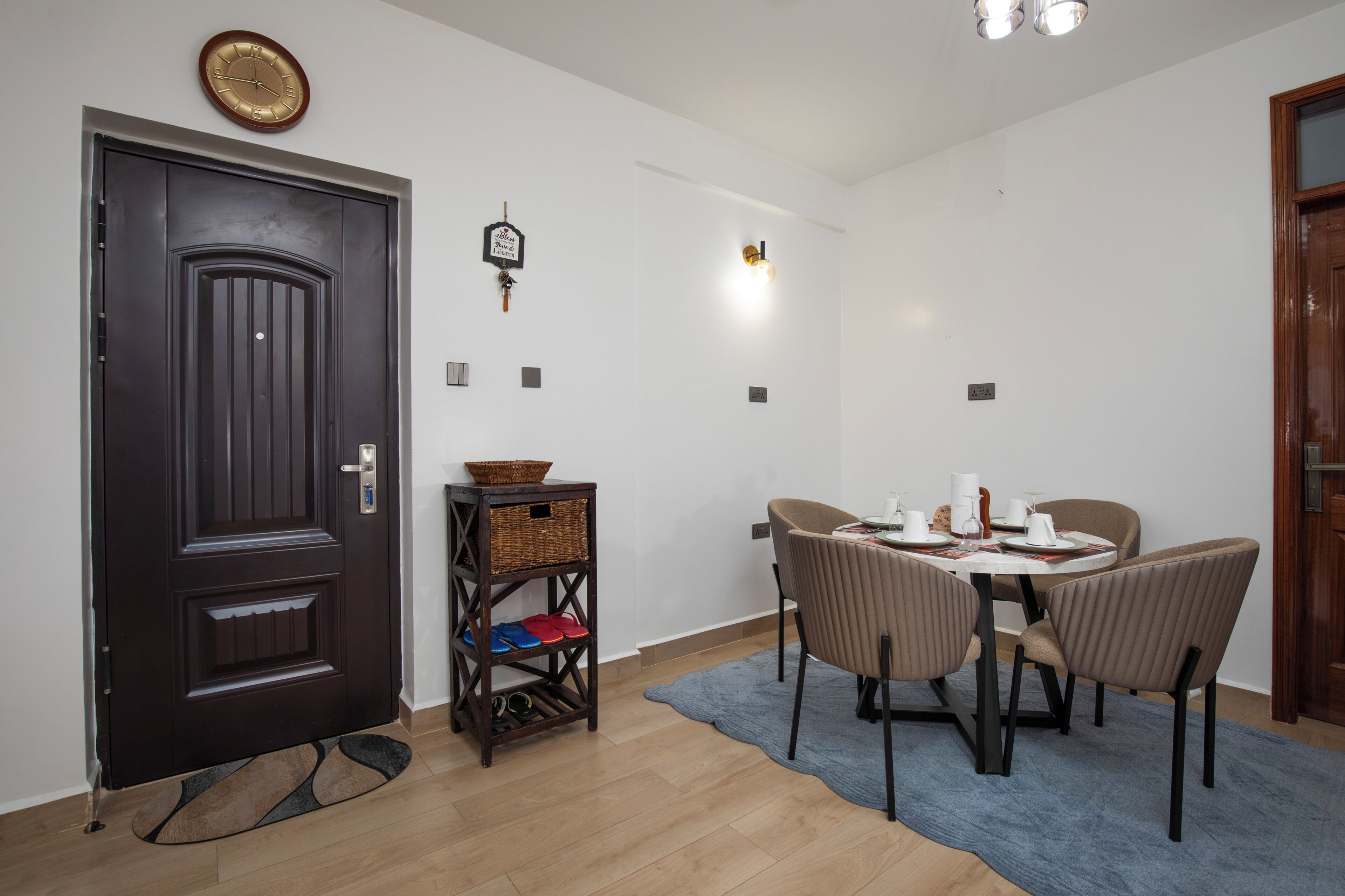 Un comedor con una mesa redonda, sillas, un reloj y una puerta.