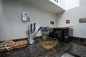 A kitchen with a marble countertop, a microwave, a toaster, and various utensils. - Comfort Suite 2-Bed Apartment in Westlands, next to Mövenpick Nairobi Hotel (Nairobi)