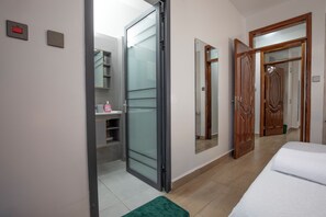 A bedroom with a bed, a bathroom with a shower, and a hallway with doors. - Comfort Suite 2-Bed Apartment in Westlands, next to Mövenpick Nairobi Hotel (Nairobi)