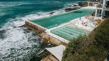 Piscina frente al mar con vistas al océano, una torre de salvavidas y un edificio con balcón.