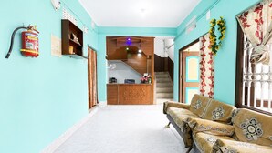 A living room with a sofa, a staircase, and a kitchen area. - Radha Krishna Homes - near Sea Beach (Puri)