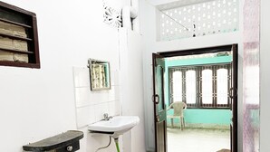 A bathroom with a sink, mirror, and a door leading to a balcony. - Radha Krishna Homes - near Sea Beach (Puri)
