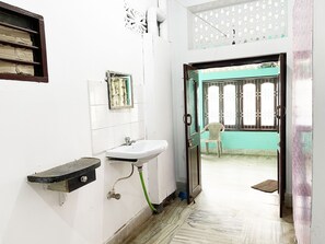 A bathroom with a sink, mirror, and a door leading to a balcony. - Radha Krishna Homes - near Sea Beach (Puri)