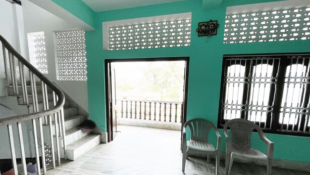 A staircase leading to a balcony with a view, a chair, and a decorative wall panel. - Radha Krishna Homes - near Sea Beach (Puri)