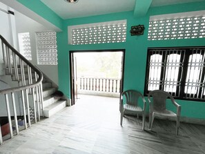 Escadaria que leva a uma varanda com vista, uma cadeira e um painel decorativo na parede.