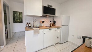 Una cocina moderna con armarios blancos, un microondas integrado y un fregadero.