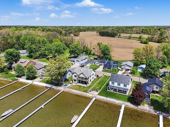 An aerial view of a residential area with houses, green lawns, and a large open field.