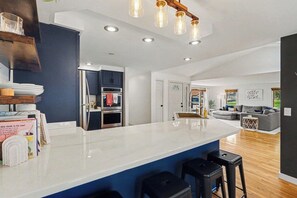 Una cocina moderna con una isla grande, horno empotrado e iluminación colgante.