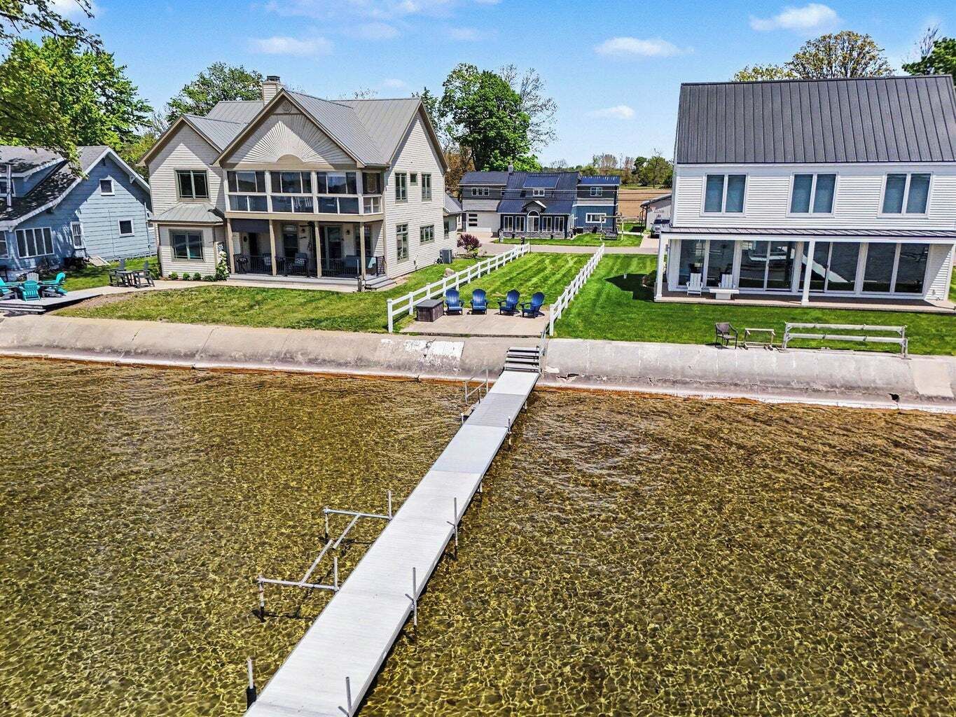 A residential area with houses, a clear water body, and a concrete walkway.
