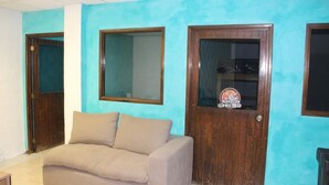 A room with a teal wall, a beige sofa, and two wooden doors with glass panels.